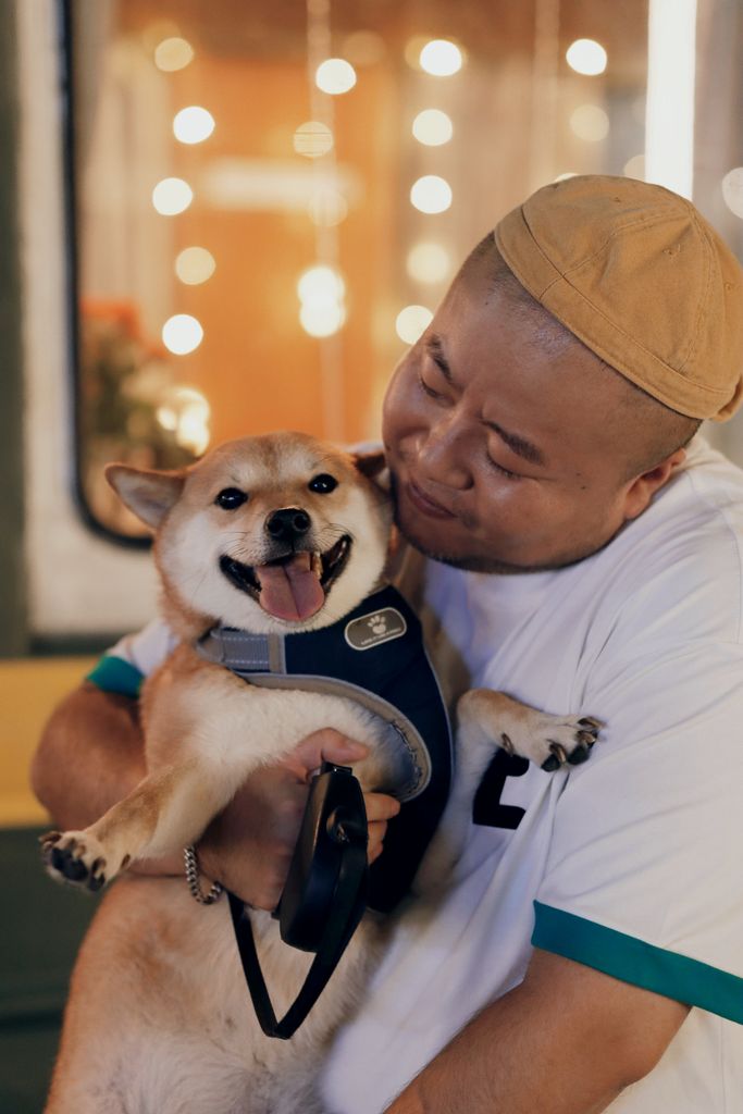 A joyful moment between a man and his Shiba Inu dog captured at night with blurred lights.